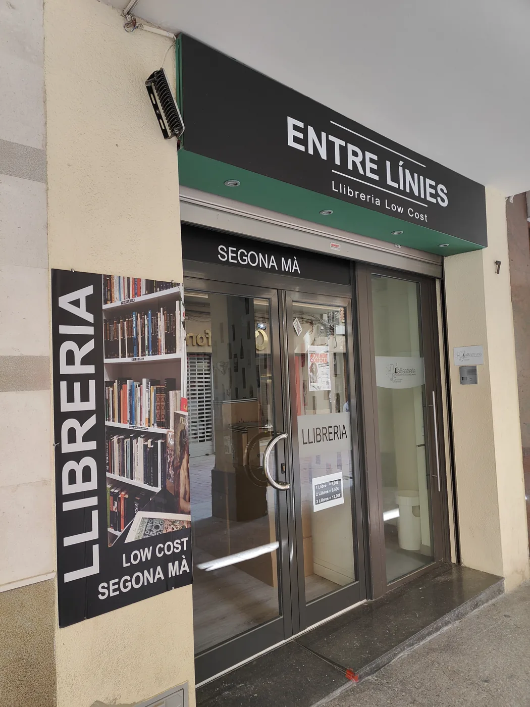 La façana de la llibreria al carrer de la Cort, amb el rètol Entre Línies i els vinils de Segona mà i Low cost